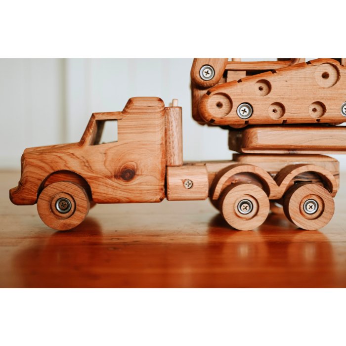 Close up of Ballard Bear premium handmade wooden truck cab hauling dozer construction toys. Showcasing suspension, smoke stacks and realistic features.