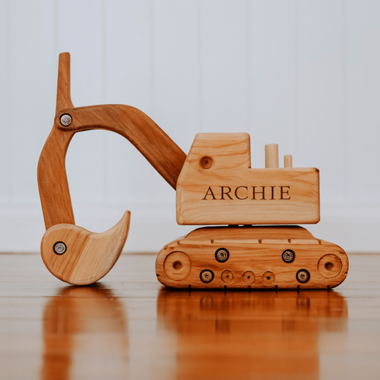 Wooden toy excavator with 'ARCHIE' branding on a reflective surface.