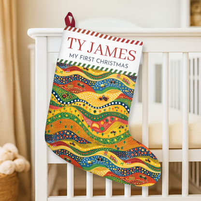 Colorful Christmas stocking with 'TY JAMES MY FIRST CHRISTMAS' text on a white crib.