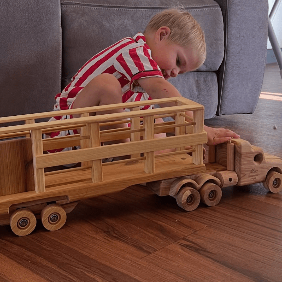 A Young Boy happily playing with a HUGE Handmade Wooden Truck Heirloom, personalised with family business logo.
