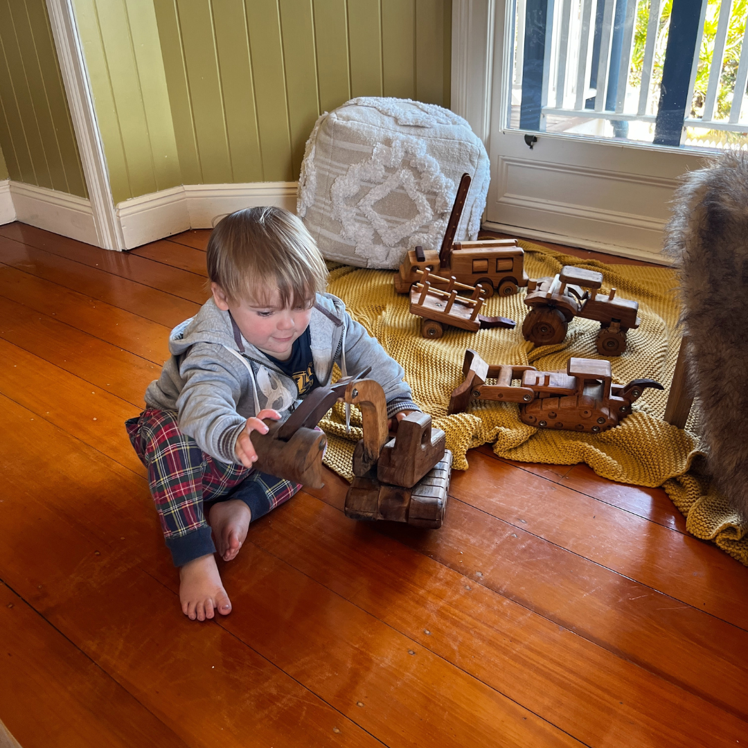 A young boy playing with a heirloom digger, dozer and truck. Personalised details on the wooden vehicles.