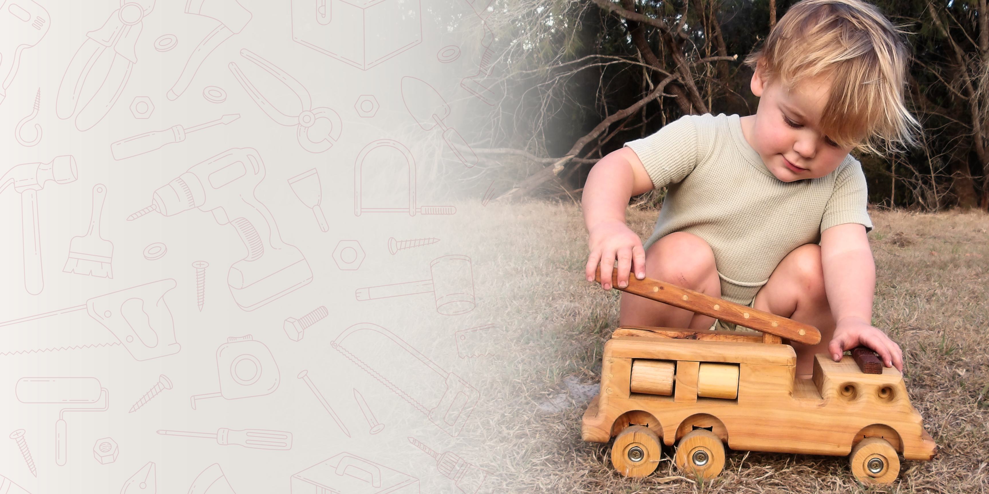 A young boy happily playing with Heirloom Handmade Wooden Firetruck. Luxury, exclusive. 