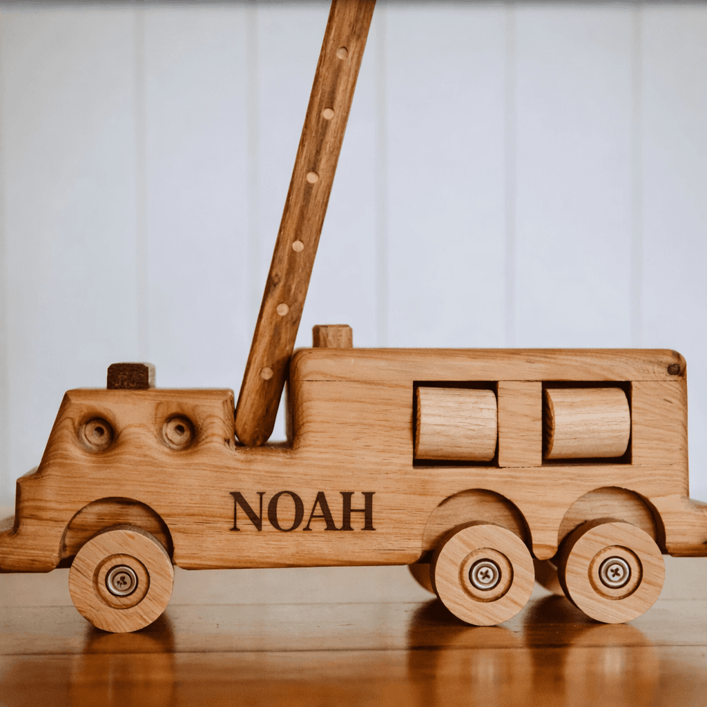 Wooden toy truck with 'NOAH' engraved on a wooden surface