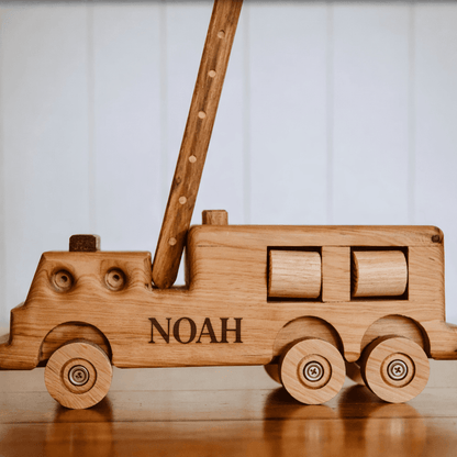 Wooden toy truck with 'NOAH' engraved on a wooden surface