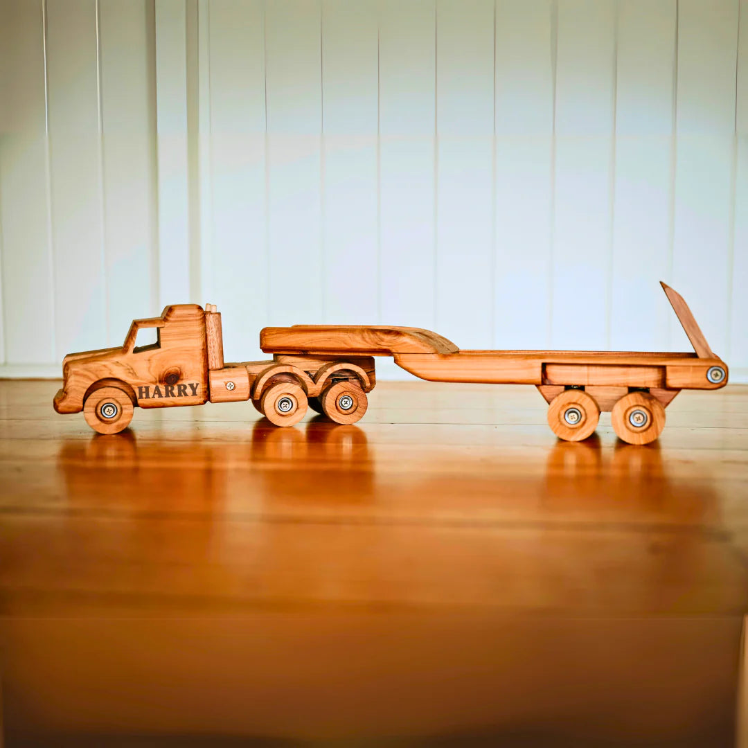 Wooden toy truck with 'HARRY' branding on a wooden surface.