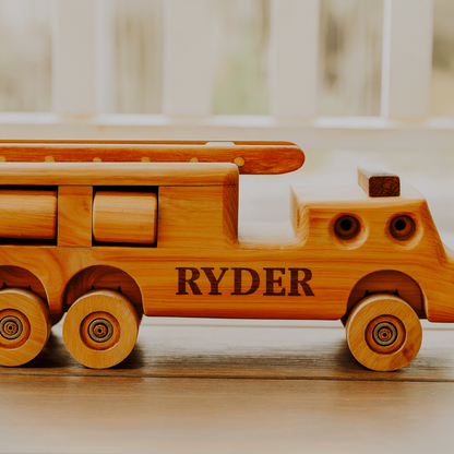 Wooden toy truck with 'RYDER' engraved on a wooden surface