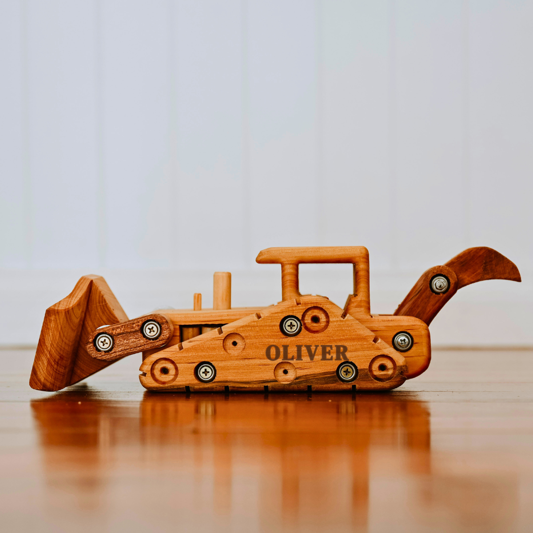 Wooden toy bulldozer with 'OLIVER' branding on a wooden surface.