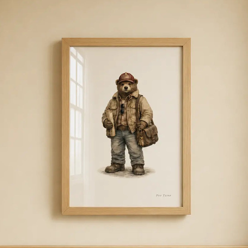 A framed art print of a teddy bear character wearing a hat and jacket, hanging on a beige wall above a light wood crib. road train