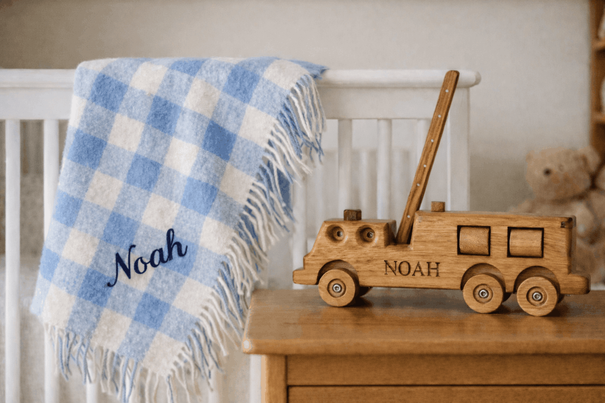 Handcrafted wooden firetruck heirloom engraved “ARMSTRONG” displayed on a cream stone fireplace mantel in an Australian farmhouse, with a vintage 1940s Australian firefighter portrait in the background.