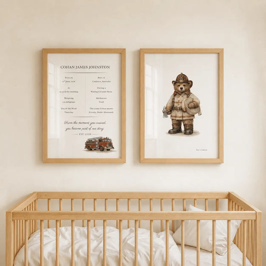 Two framed nursery wall prints hang above a wooden crib in a softly lit room. The left print is a personalized memorial-style text layout with a small train illustration, and the right print shows a teddy bear dressed as a firefighter. fire truck