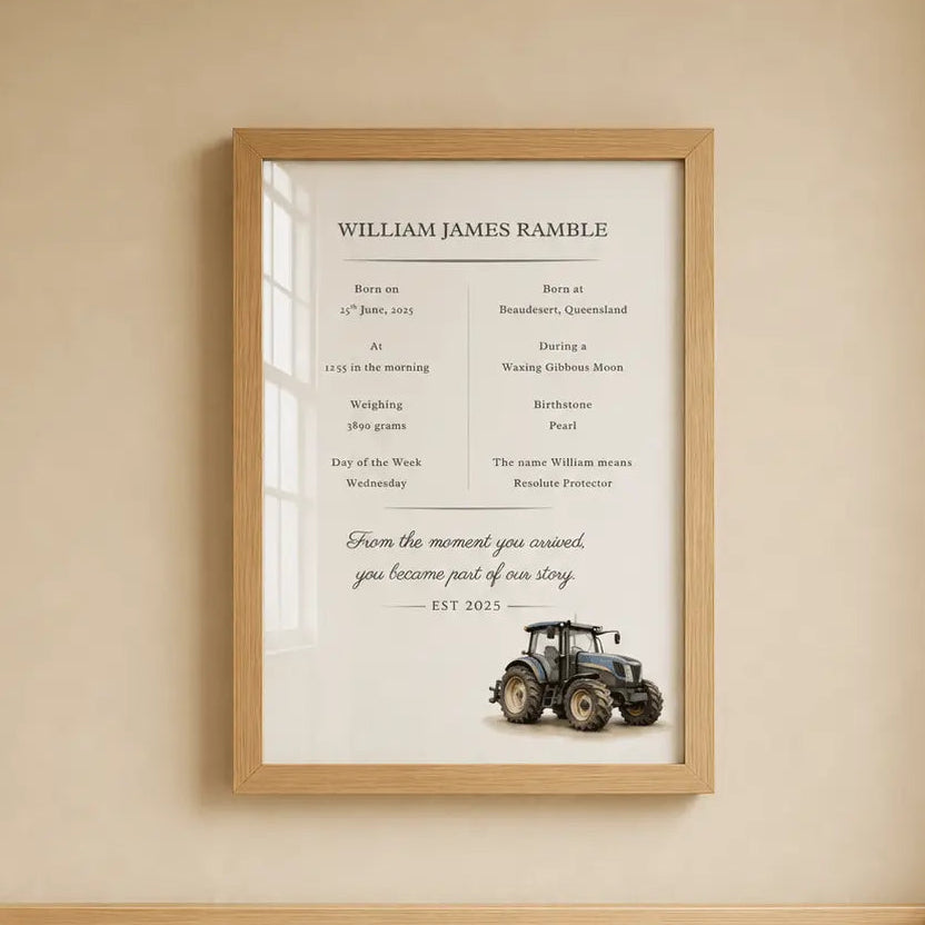 A framed personalized baby milestone print hangs on a beige wall above a wooden crib. The print features a white background with black text detailing a baby's birth and growth, signed 'William James Ramble' at '2025', and includes a small tractor illustration at the bottom. Tractor 